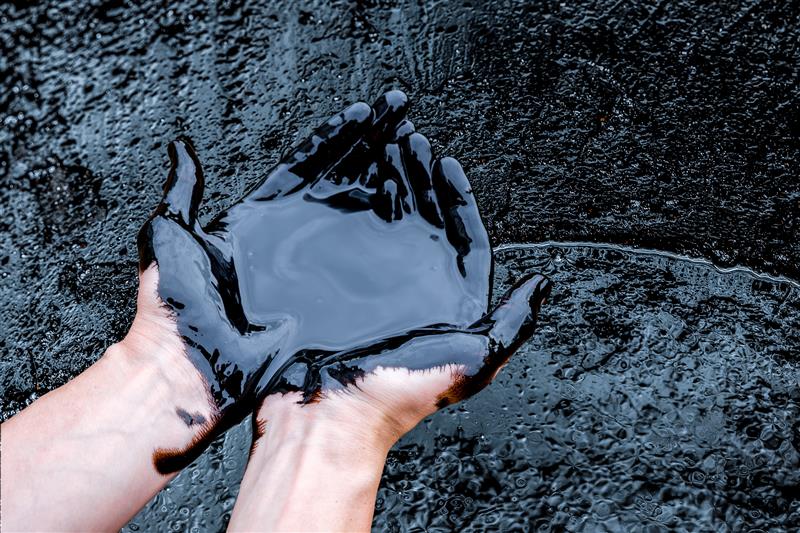 Zwei Hände in Erdöl eingetaucht.