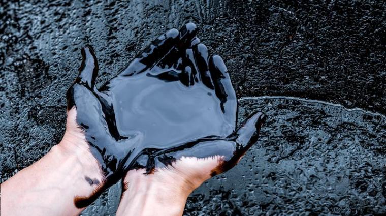 Zwei Hände in Erdöl eingetaucht.