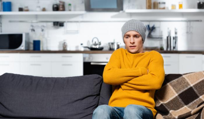 Person sitting on couch with hat, freezing. 