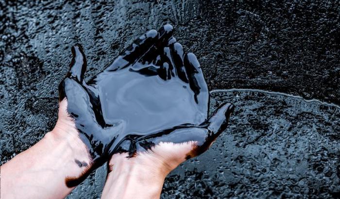 Zwei Hände in Erdöl eingetaucht.