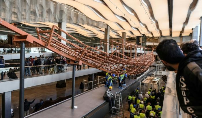 Des employés installent des planches de bois anciennes provenant de la deuxième barque du roi Khéops sur une structure métallique au Grand Musée égyptien de Gizeh, en périphérie du Caire, le 23 décembre 2025
