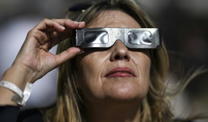 Une femme observe avec des lunettes protectrices une éclipse solaire partielle à Ericeira, au Portugal, le 29 mars 2025
