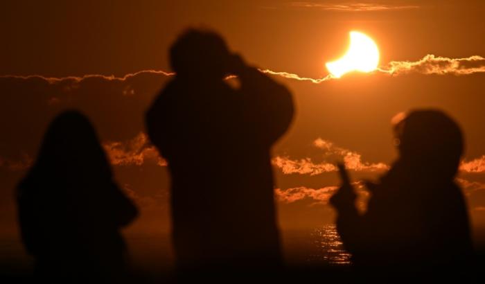 Des gens ovbservent une éclipse solaire partielle à New Brighton, banlieue côtière de la région de Christchurch, en Nouvelle-Zélande, le 22 septembre 2025