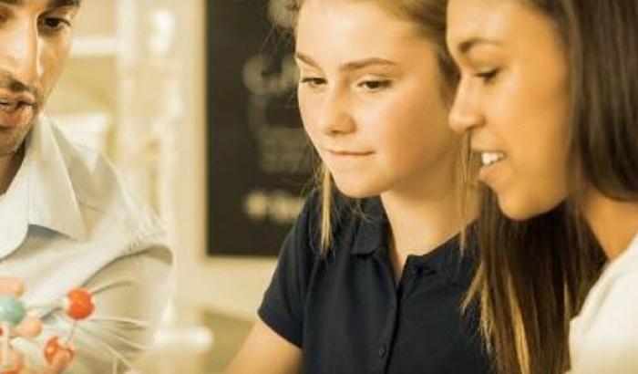 two girls looking at model of molecule