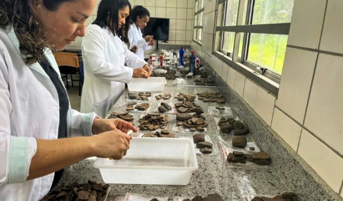 Photo diffusée par WLage Arqueologia montrant des archéologues examinant des fragments de céramique trouvés lors de fouilles sur un chantier de construction à Sao Luis, dans l'État du Maranhao, le 29 mars 2023 au Brésil