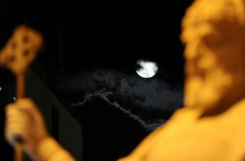 La lune est visible derrière une statue du tsar Samouil, l'un des derniers souverains bulgares avant la domination byzantine, au centre de Skopje, en Macédoine du Nord, le 25 mai 2013