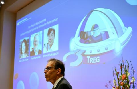 Le secrétaire général du comité Nobel, Thomas Perlmann, devant un écran affichant les portraits (g-d) de Mary E Brunkow, Fred Ramsdell et Shimon Sakaguchi co-lauréats du prix Nobel de médecine, lors d'une conférence de presse sur leurs travaux à l'Institut Karolinska de Stockholm, en Suède, le 6 octobre 2025