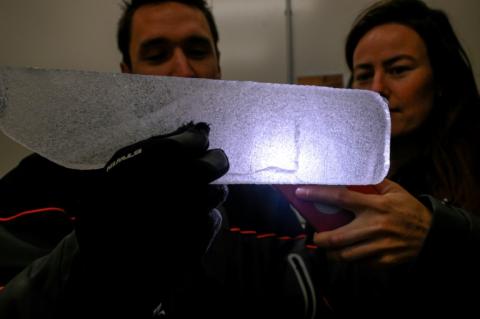 Des scientifiques examinent à la lumière d'un téléphone portable une carotte glaciaire antarctique dans un laboratoire à Bruxelles, le 15 juillet 2025 en Belgique