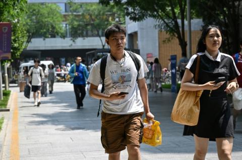 Un étudiant chinois devant l'Université des études internationales de Pékin, portant un t-shirt sur le marathon de New York, le 29 mai 2025