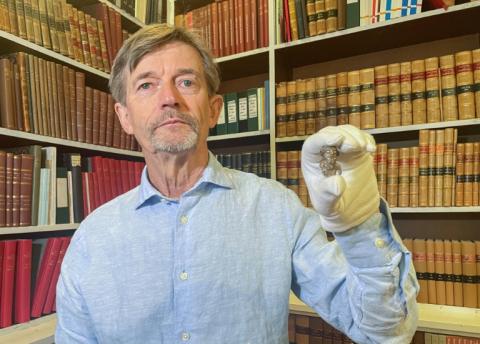 Le conservateur du musée national du Danemark, Peter Pentz, montre une figurine en ivoire de morse, pièce d'un jeu de société, qui serait le premier portrait d'un Viking, le 26 août 2025 à Copenhague