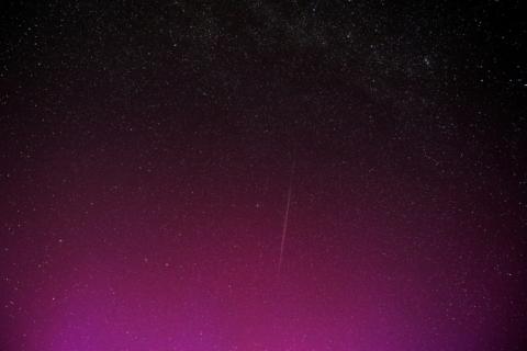 Une photo en pose longue montre une traînée laissée par un groupe de satellites Starlink de SpaceX, dans un ciel illuminé par des aurores boréales pendant la pluie annuelle d'étoiles filantes des Perséides, le 12 août 2024 à Wigry, en Pologne