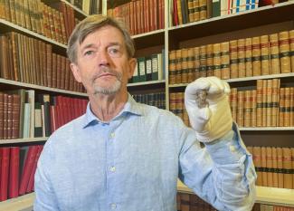 Le conservateur du musée national du Danemark, Peter Pentz, montre une figurine en ivoire de morse, pièce d'un jeu de société, qui serait le premier portrait d'un Viking, le 26 août 2025 à Copenhague