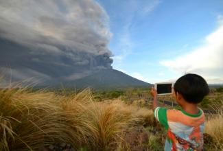 Un enfant photographie une éruption du mont Agung, sur l'île indonésienne de Bali, le 21 décembre 2017