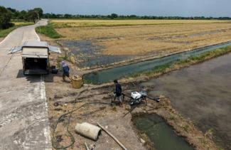 Des opérateurs de drones agricoles s'apprêtant à pulvériser des solutions microbiennes sur les chaumes d'une rizière dans la province de Pathum Thani, en Thaïlande, le 30 mars 2026