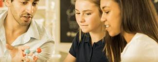 two girls looking at model of molecule