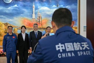 Zhang Jingbo (C), porte-parole du Programme spatial habité de la Chine, avec des membres du personnel après une conférence de presse sur la mission spatiale habitée Shenzhou-21, un jour avant le lancement de la mission au Centre de lancement de satellites de Jiuquan à Jiuquan, dans la province de Gansu, le 30 octobre 2025
