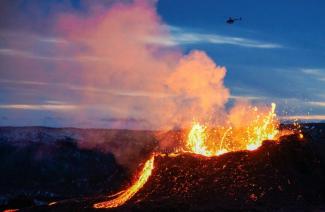 Un hélicoptère survole une coulée de lave en fusion près du mont Fagradalsfjall, à une quarantaine de kilomètres de Reykjavik, le 6 avril 2021 en Islande